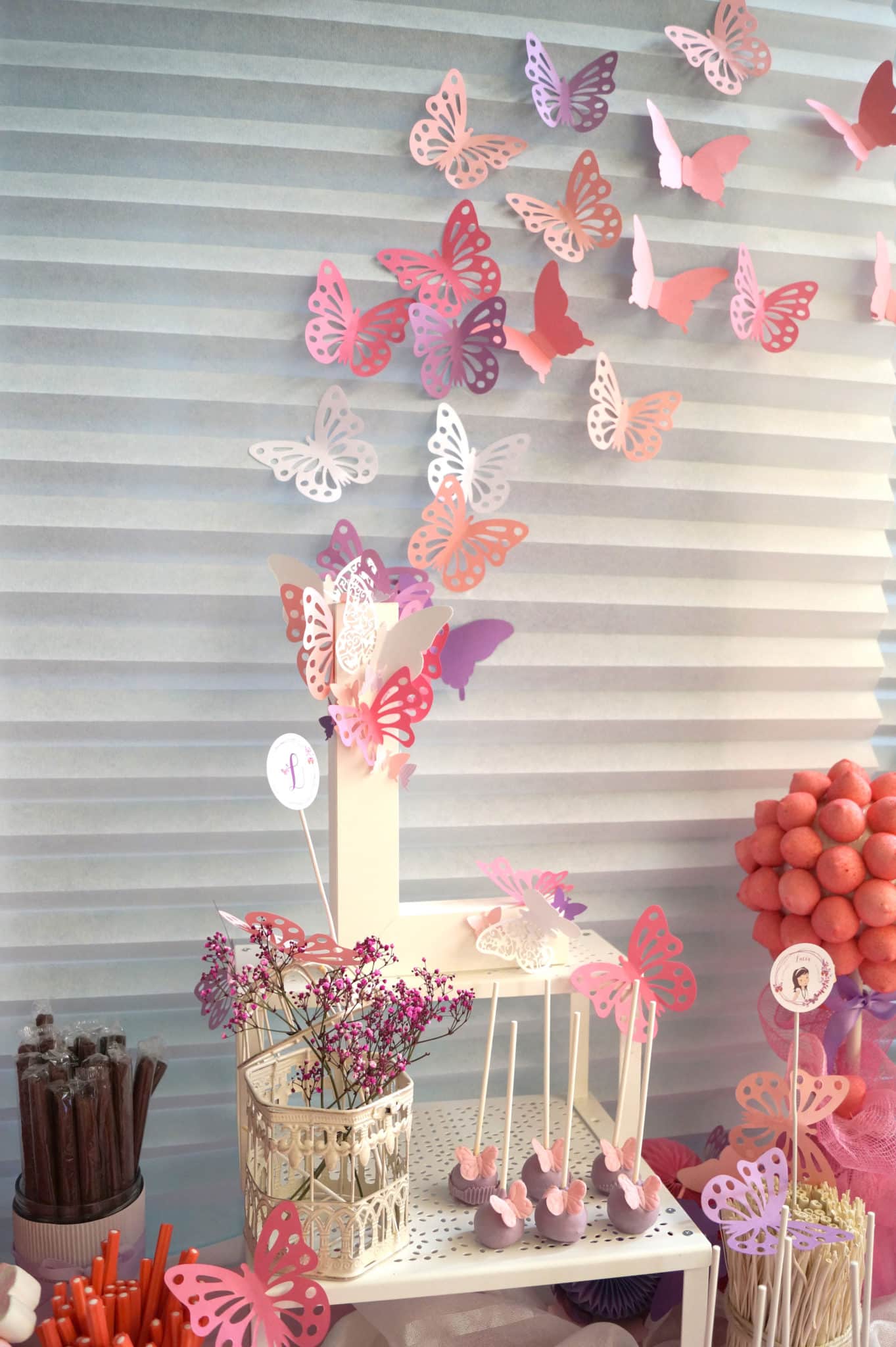 Detalle mesa dulce comunión en tonos rosas y morados con mariposas