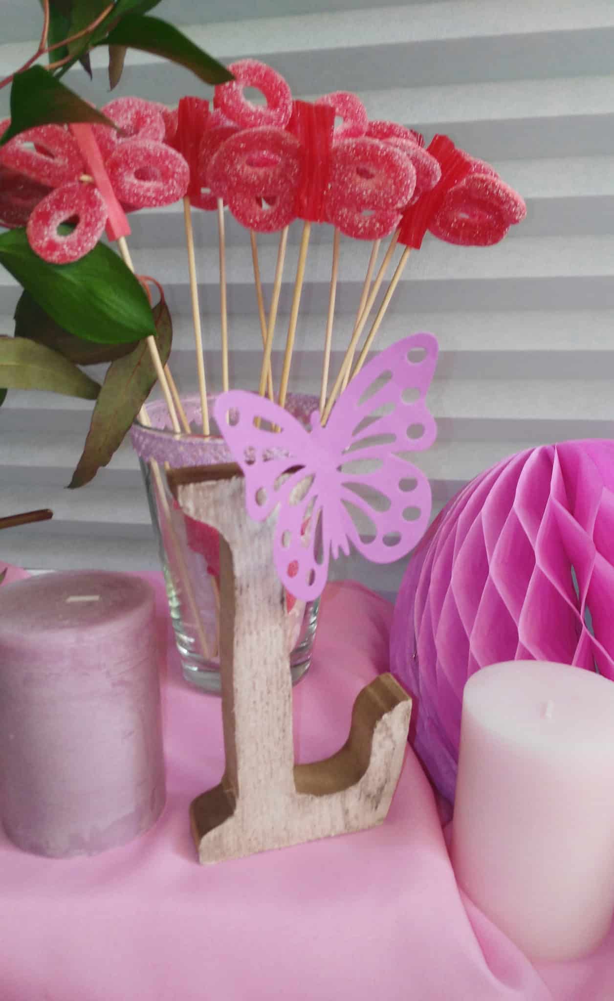 Detalle mesa dulce comunión en tonos rosas y morados con mariposas